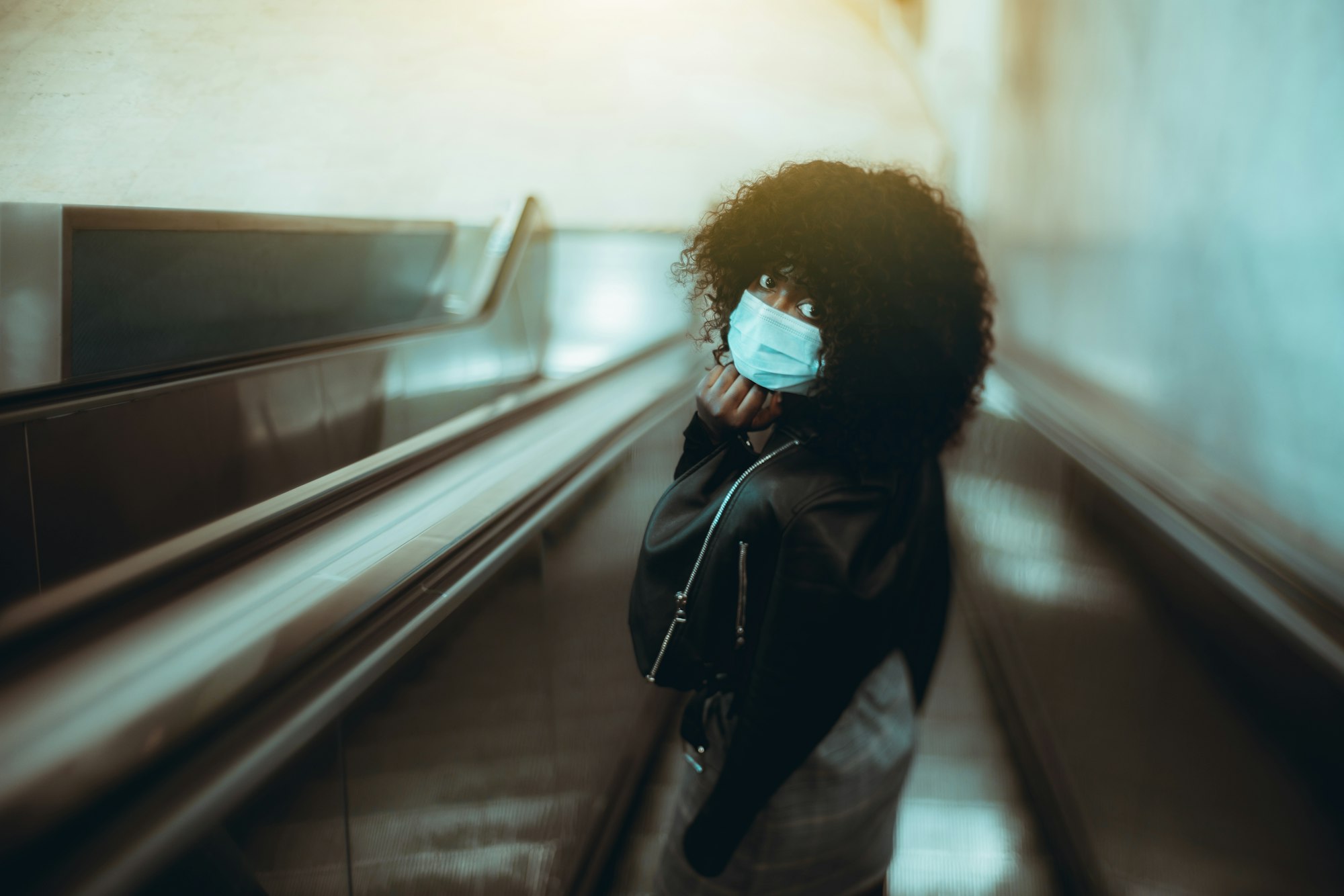 Black girl in a mask on an escalator